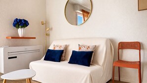 A modern room with a sofa, a chair, a round mirror, a small table, and a radiator. - Charming appartment La Pironnière - Les Sables - 4 people (Les Sables-d´Olonne)