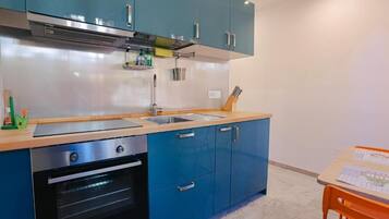 Una cocina con armarios azules, una campana extractora de acero inoxidable, un fregadero y un horno.