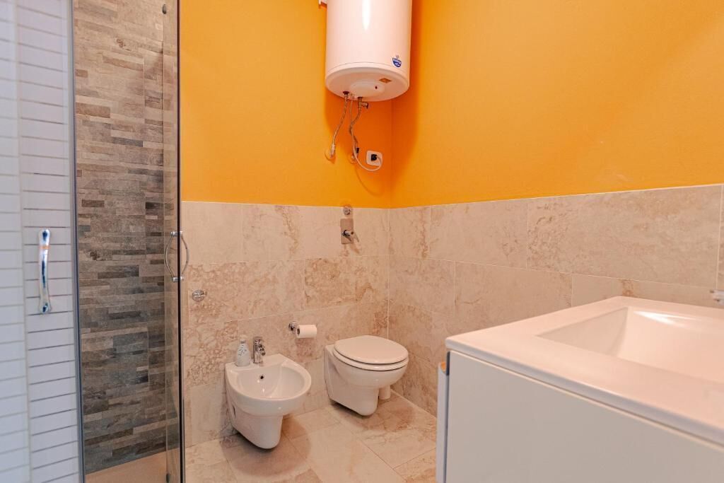 A bathroom with a glass shower enclosure, a toilet, a bidet, and a bathtub.