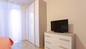 Una camera da letto con un letto, una televisione su una cassettiera e una finestra con tende.