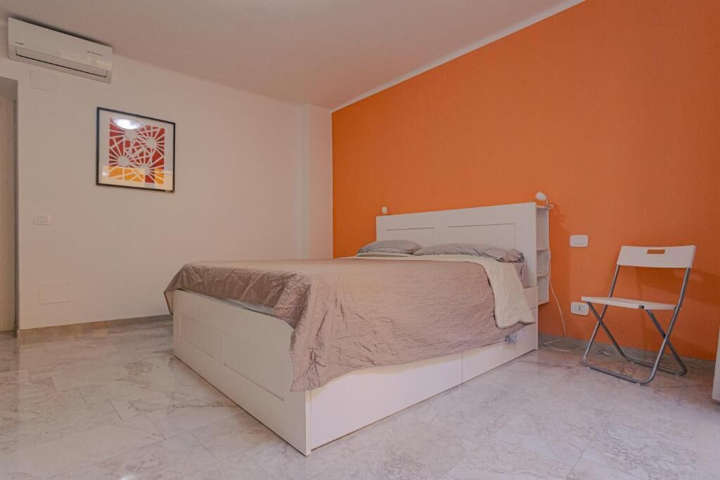 A bedroom with a bed, a chair, and an air conditioning unit.