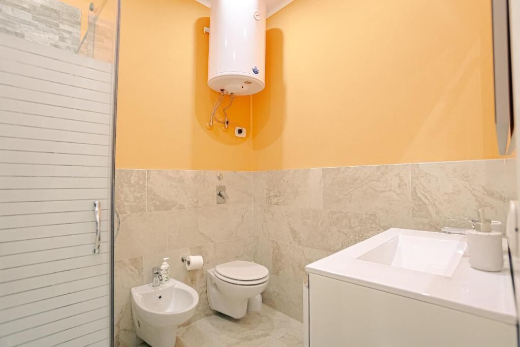 A bathroom with a toilet, bidet, sink, and a towel rack.