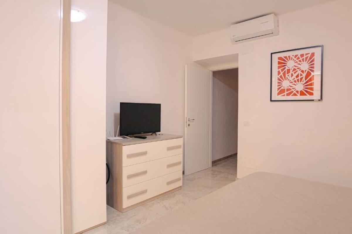 A room with a television on a dresser, a door, and a framed picture on the wall.