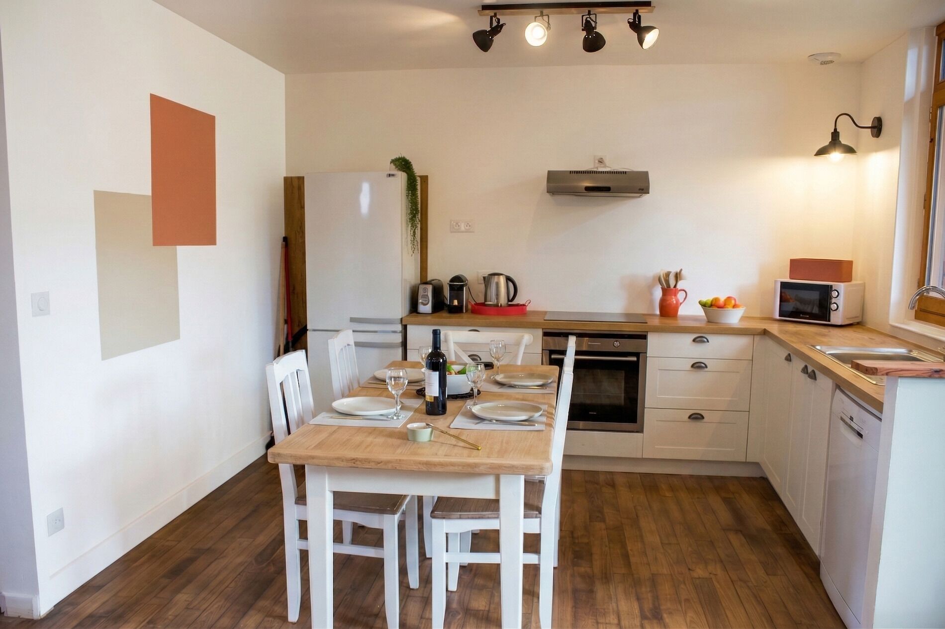 Een compacte keuken met een eettafel, stoelen, een koelkast, een magnetron en een fornuis.