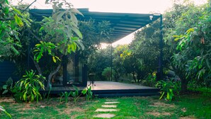 A garden with a wooden deck, stone pathway, and various plants. - Amram (Shoolagiri)