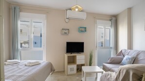 Ein Hotelzimmer mit Bett, Sofa, Fernseher, kleinem Tisch und Fenster.