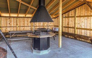A wooden interior with a central stove, benches, and a high ceiling.