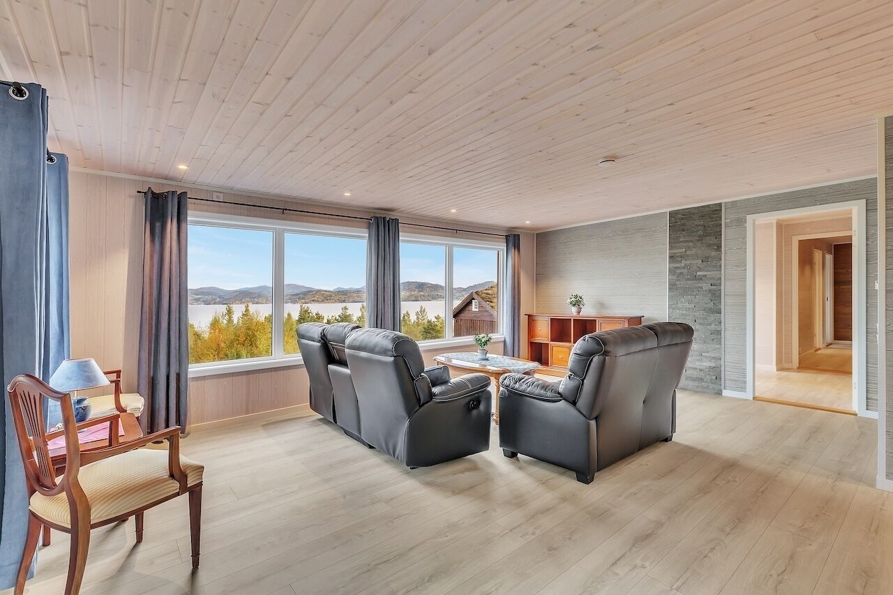 A spacious living room with a large window, a sofa set, a wooden coffee table, and a view of the outdoors.