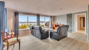 A spacious living room with a large window, a sofa set, a wooden coffee table, and a view of the outdoors.