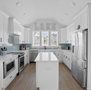 A modern kitchen with white cabinetry, stainless steel appliances, and a central island.