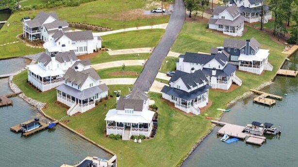 A lakeside residential area with multiple houses connected by a central pathway, docks, and boats. - Lake Happy - Waterfront Paradise (Dadeville)