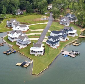A lakeside residential area with multiple houses connected by a central pathway, docks, and boats. - Lake Happy - Waterfront Paradise (Dadeville)