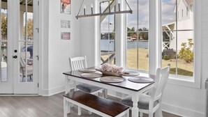 A dining area with a white table, chairs, and a hanging light fixture. - Lake Happy - Waterfront Paradise (Dadeville)