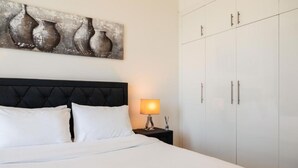 Een hotelkamer met een bed, een nachtkastje met een lamp en een kledingkast.