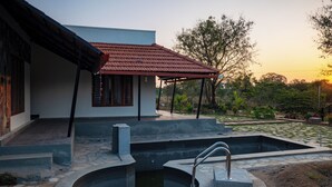 A modern house with a stone pool, a covered patio, and a garden. - Bodhi (Shoolagiri)