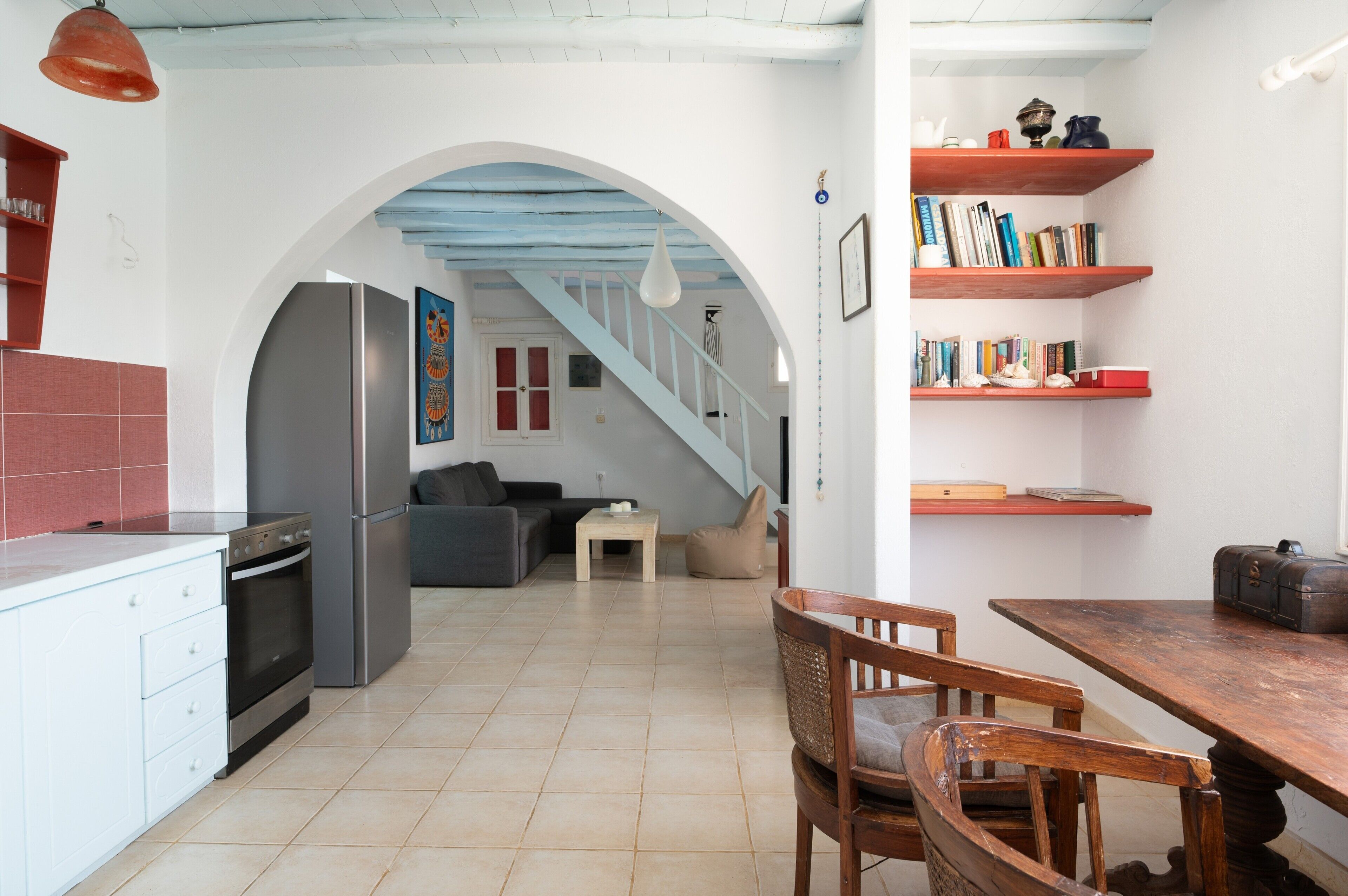 A kitchen with a refrigerator, stove, and dining area with chairs and a table.
