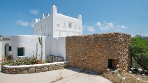 Un edificio blanco con pared de piedra, una ventana pequeña y una puerta.