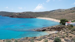 Un paisaje costero con playa, terreno rocoso y algunos edificios.