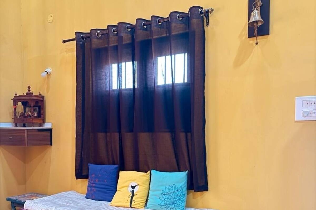 Una habitación con cama, una mesita, un armario y un timbre en la pared.