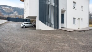 A modern building with a car parked in front, a staircase, and a view of a mountainous landscape. - Apartment 'Talferblick Burg' with Mountain View, Private Terrace and Wi-Fi (Sarentino)