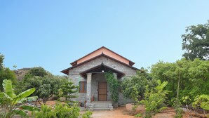 A stone house with a red roof, surrounded by greenery. - Arokiya (Shoolagiri)