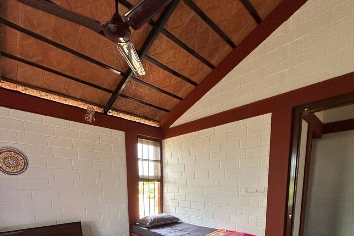 Una habitación con dos camas, ventilador de techo, piso estampado y ventana.