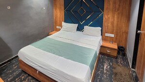 A modern bedroom with a bed, wooden headboard, nightstands, and a ceiling fan. - Hotal Park View (Ahmedabad)