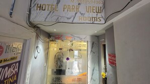 A hotel entrance with a marble wall, a sign for 'HOTEL PARK VIEW ROOMS,' and a glass door with a 'WELCOME' sign. - Hotal Park View (Ahmedabad)