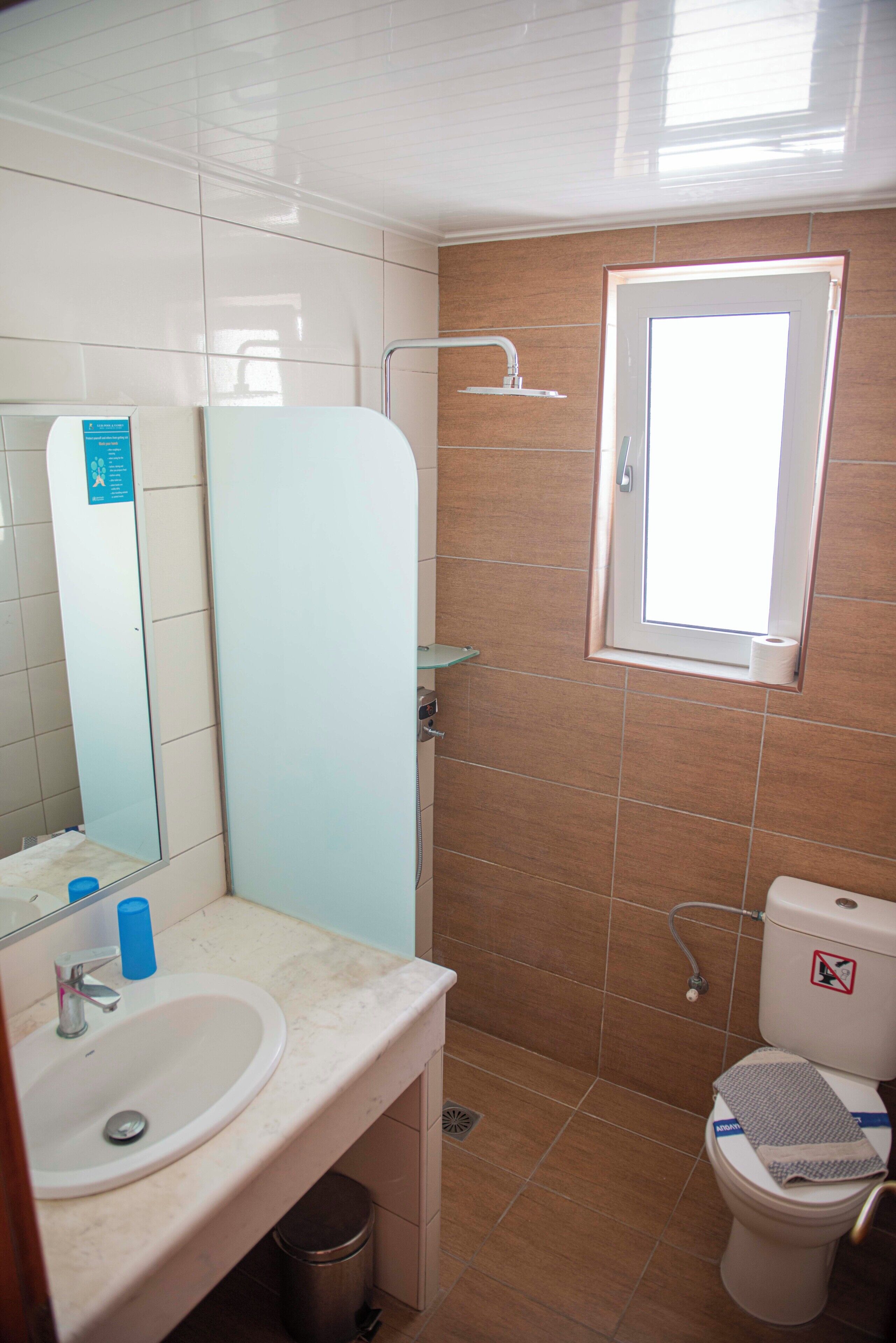 Ein Badezimmer mit Waschbecken, Spiegel, Toilette, Dusche und einem Fenster.