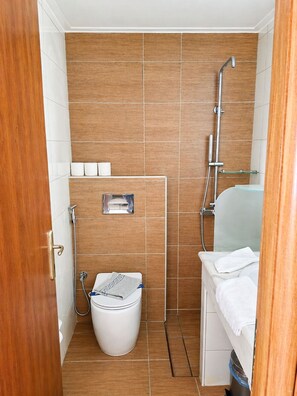 Ein kleines Badezimmer mit Dusche, Toilette und Waschbecken.