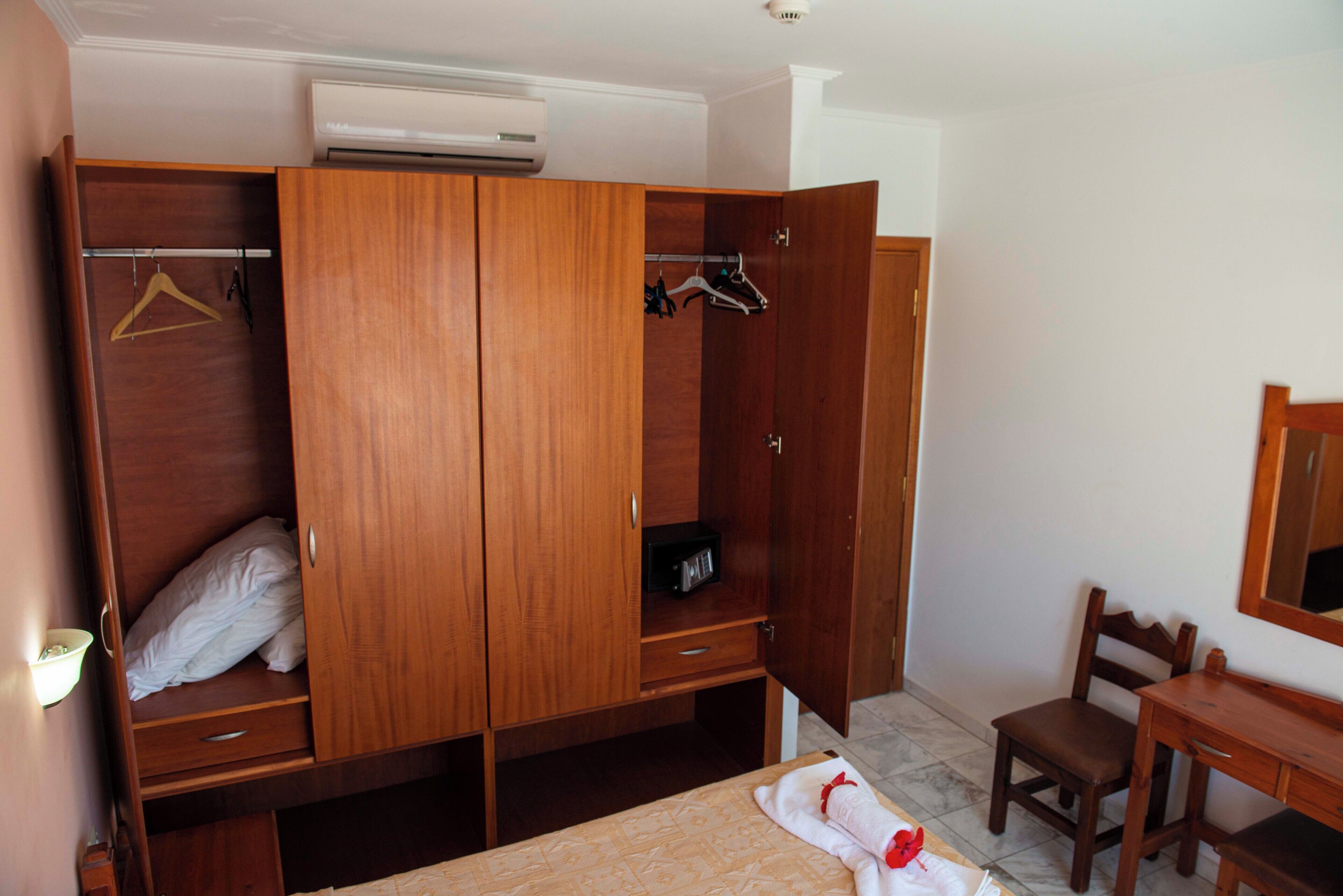 Ein Schlafzimmer mit Holzschrank, Bett, Schreibtisch und Stuhl.