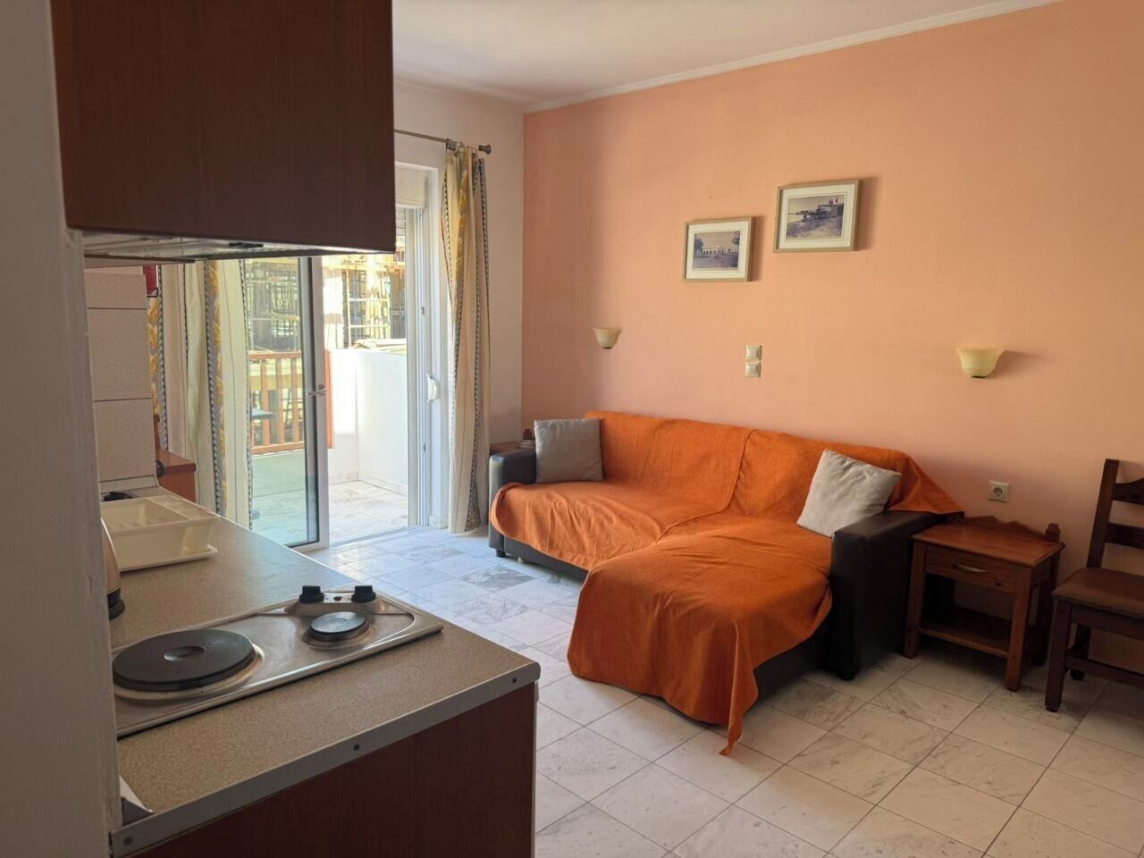 A compact living space with a kitchenette, a sofa, a chair, and a small table.