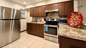 Una cocina moderna con electrodomésticos de acero inoxidable, encimeras de granito y armarios color café.