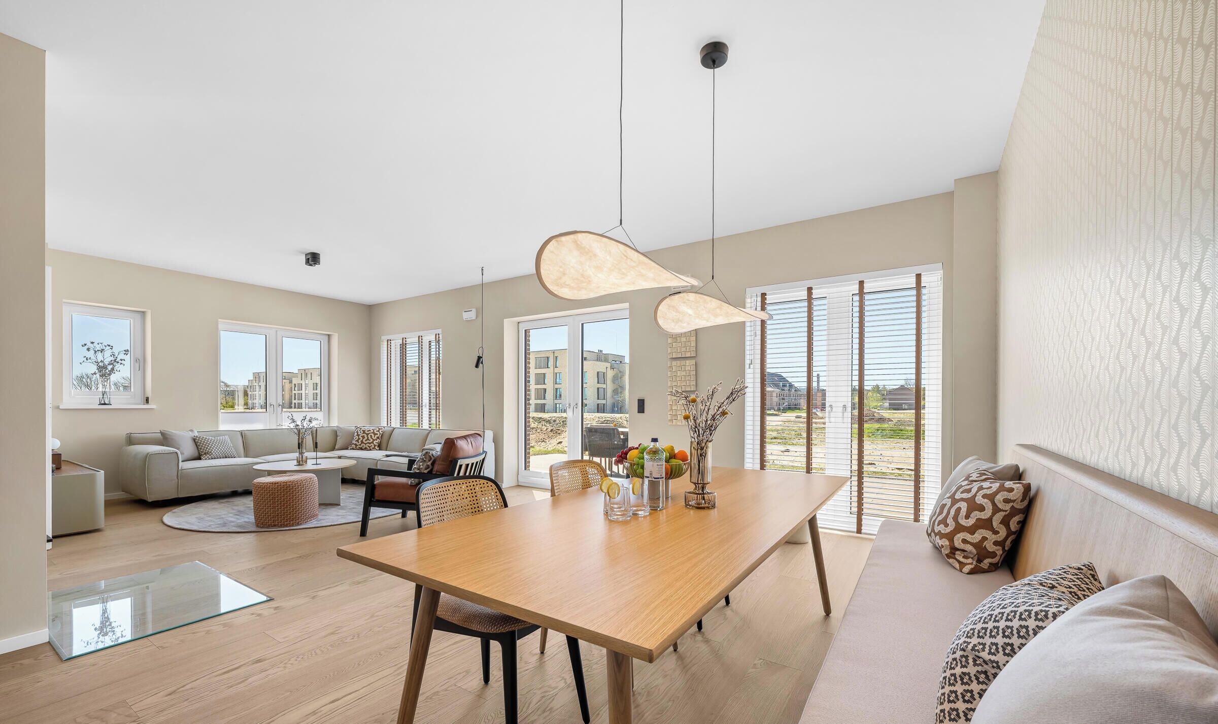 Ein geräumiges Wohnzimmer mit Essbereich, großen Fenstern und Blick ins Freie.