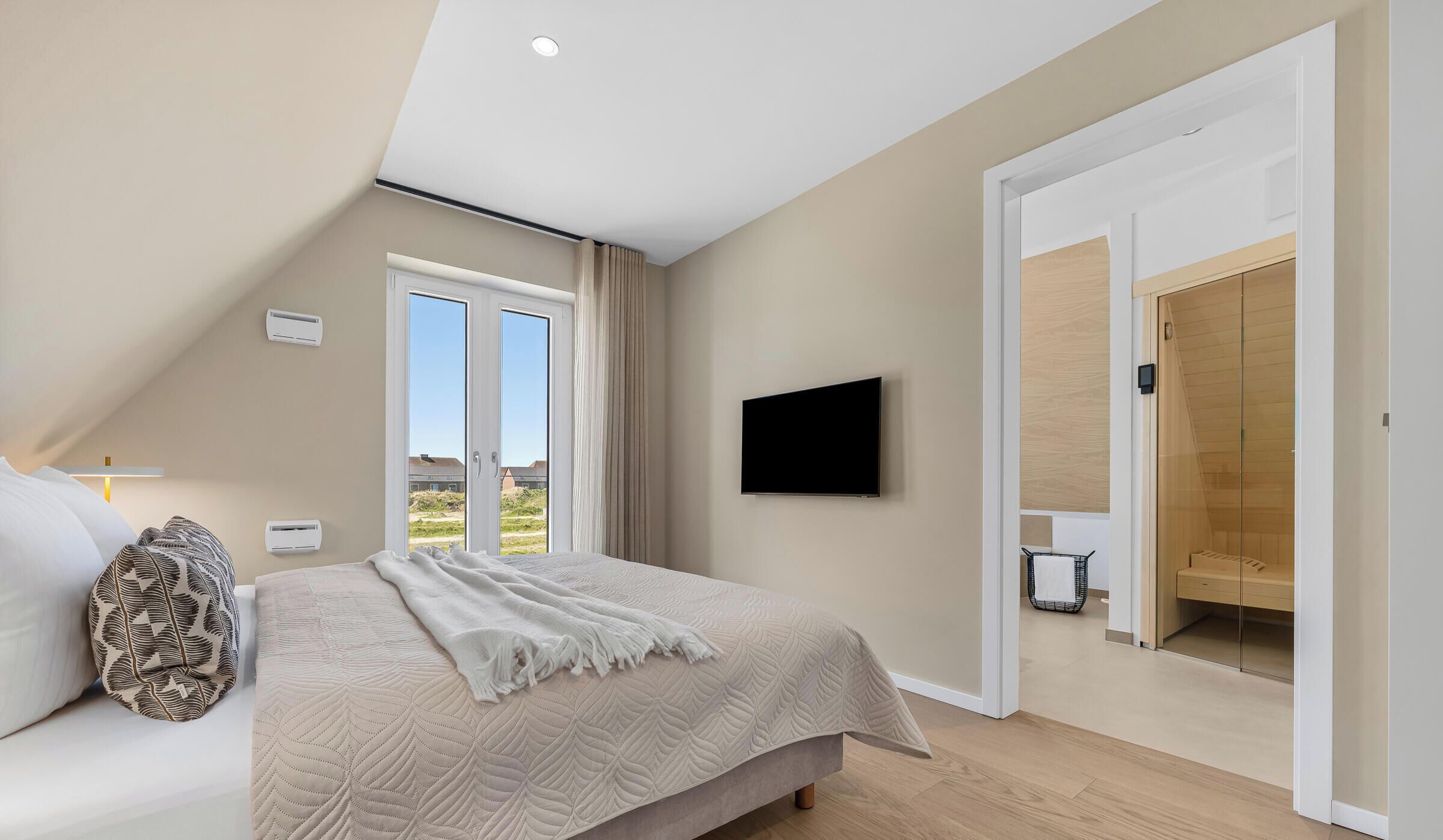 Ein Schlafzimmer mit einem Bett, einem Fernseher, einer Schiebetür und einem Deckenventilator.