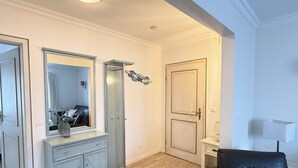 A room with a wooden floor, a black leather chair, a white door, and a mirror with a dresser. - Vacation apartment Um's Eck in Haus Inselfriede very close to the beach in Westerland (Westerland)