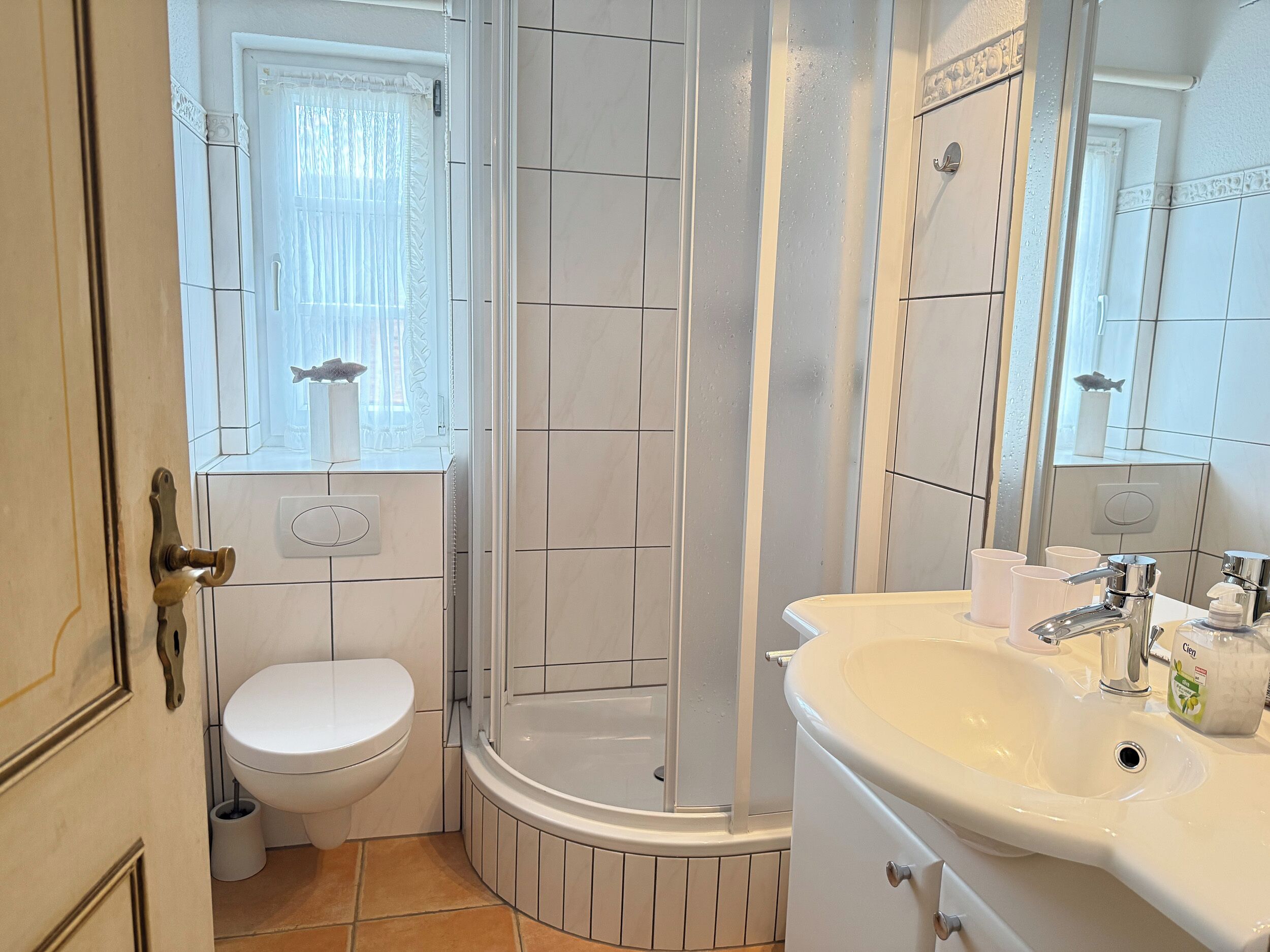 A bathroom with a toilet, shower, and sink.