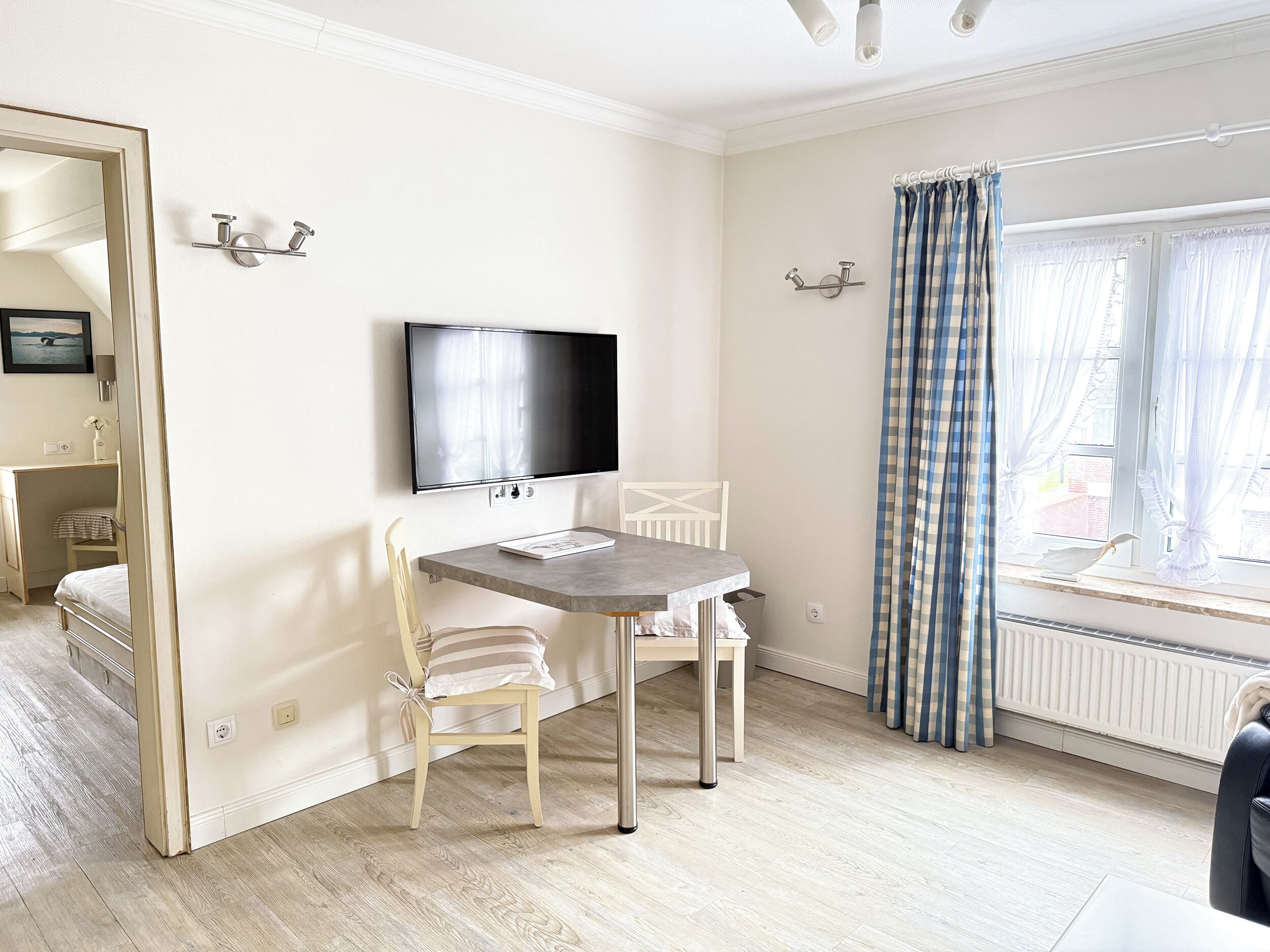 A room with a bed, a desk, a chair, a television, and a window with curtains.