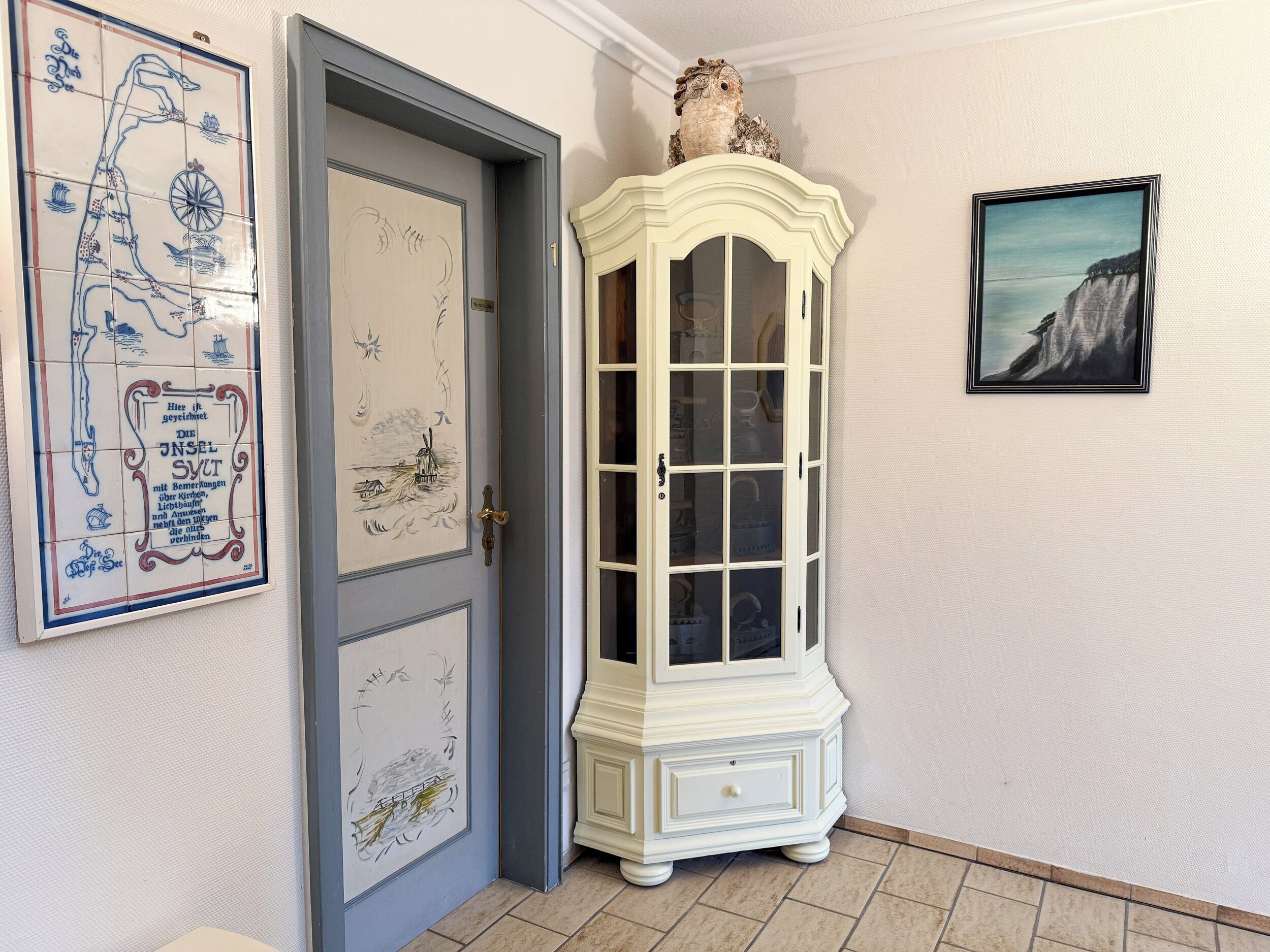 A hallway with a door, a cabinet, and a framed picture on the wall.