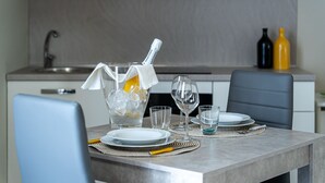 Una cocina moderna con una mesa de comedor dispuesta para dos personas, que incluye una botella de vino Santerio, copas y una jarra de vidrio transparente.