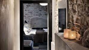 A hallway with stone walls, a bed, and a mirror. - Villa dell’Orso – Secluded Luxury with Private Infinity Pool & Piedmont Views (Piemonte)