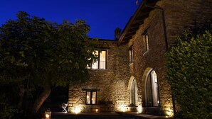A stone building with arched windows and a door, surrounded by trees. - Villa dell’Orso – Secluded Luxury with Private Infinity Pool & Piedmont Views (Piemonte)