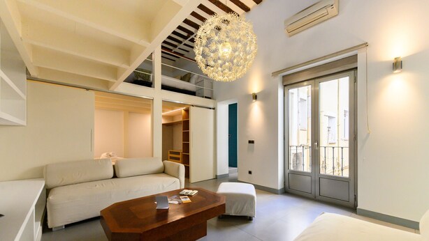 Un interno moderno con un divano, un poggiapiedi, un tavolino da caffè in legno e un lampadario.