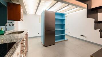 Una cocina moderna con un refrigerador empotrado, una encimera de granito y un mueble azul.