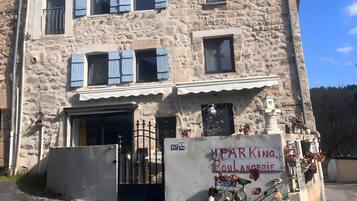 Un bâtiment en pierre doté de nombreuses fenêtres, un panneau indiquant un parking et un vélo garé à l’extérieur.