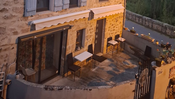A stone building with a balcony, outdoor seating, and a bicycle.