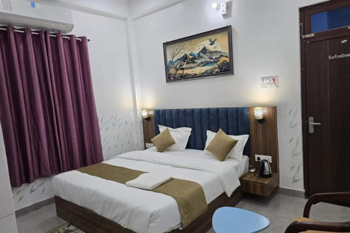 Ein Hotelzimmer mit Bett, Nachttisch, Stuhl, einem Bild an der Wand und einer Tür.