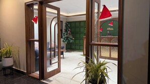 A hotel lobby with a Christmas tree, a reception desk, and a seating area. - Saraiville - Boutique Riverside Stay (Vikasnagar)