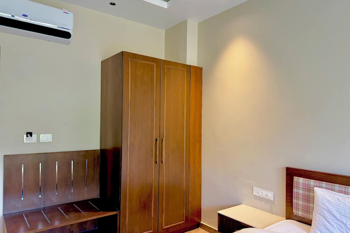 Une chambre à coucher avec une armoire en bois, un lit avec une tête de lit et une petite table de chevet.