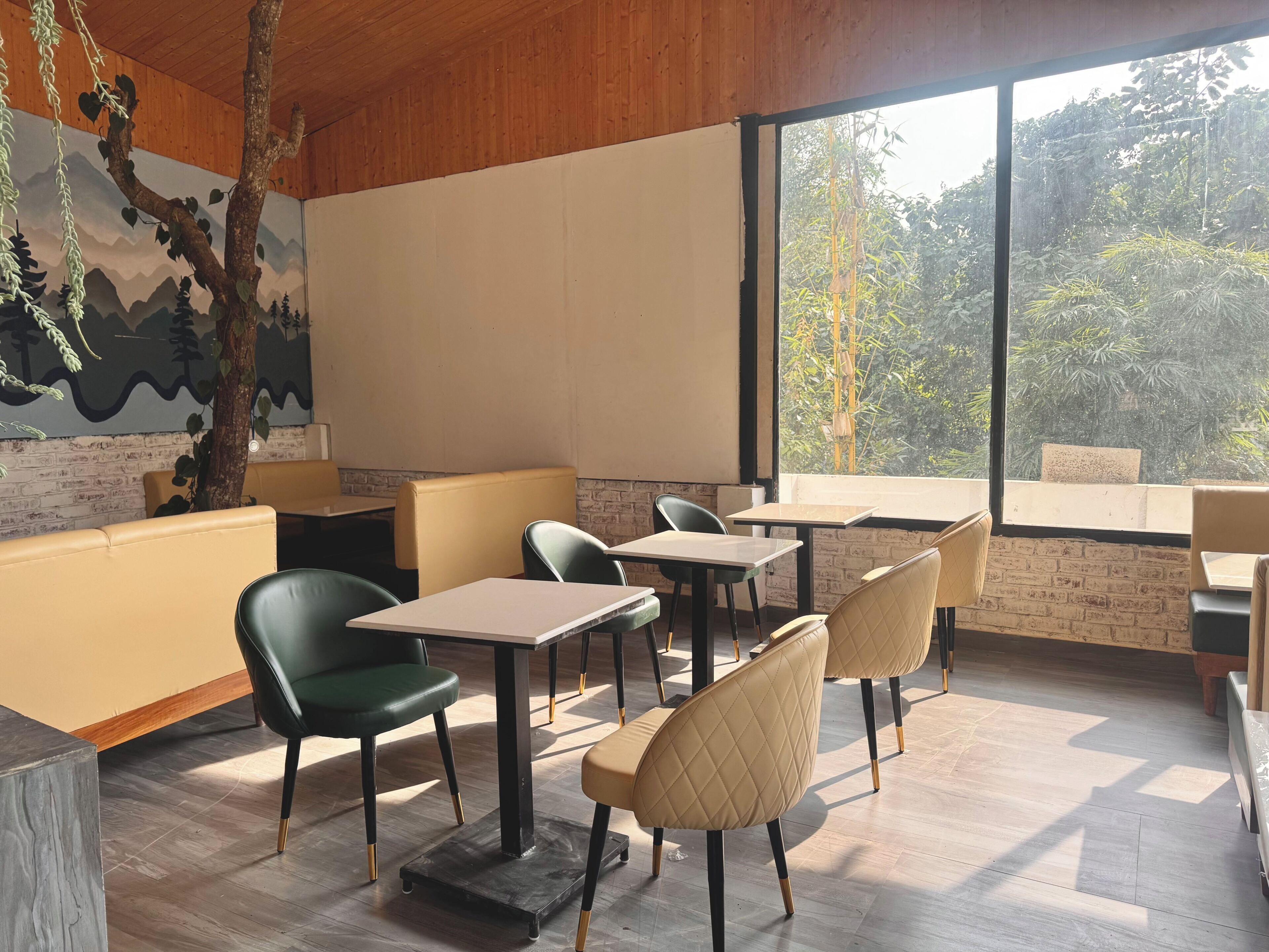 Un espace de restauration moderne avec un plafond en bois, des murs en briques et de grandes fenêtres donnant sur un paysage verdoyant.